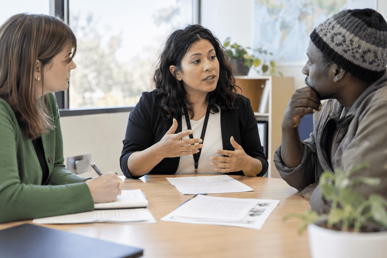 An interpreter facilitating a conversation between a staff member and a client at a meeting table